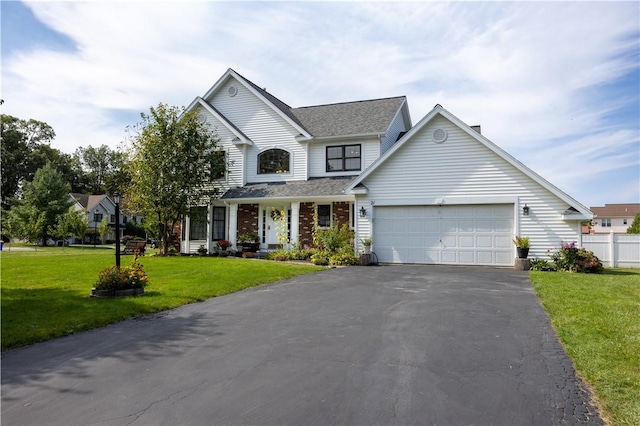 traditional-style home with driveway, an attached garage, fence, a front lawn, and brick siding