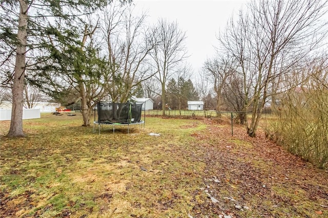 view of yard featuring a trampoline and fence