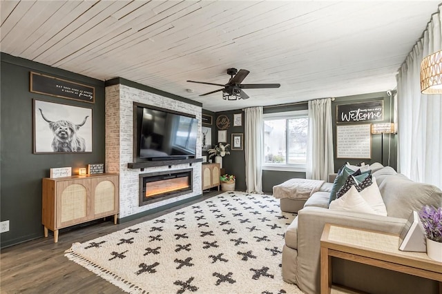 living room featuring ceiling fan, wood finished floors, a glass covered fireplace, and wood ceiling