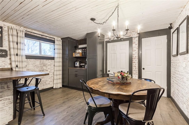 dining space featuring dark wood-style flooring, wooden ceiling, a notable chandelier, and brick wall