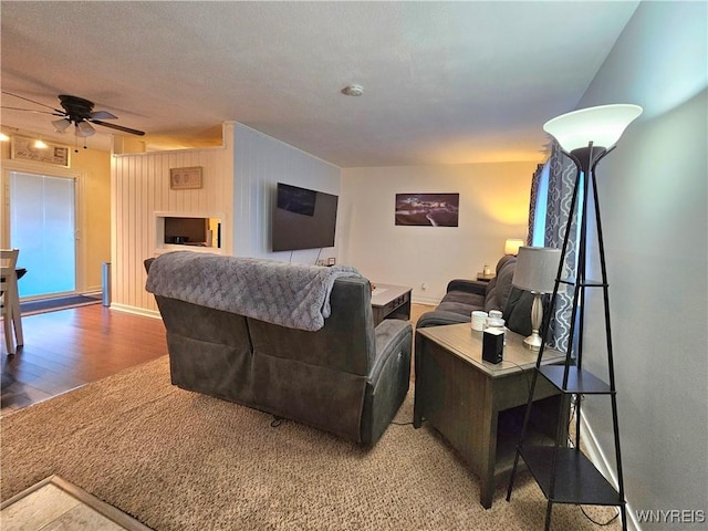 living room with wood finished floors, a ceiling fan, and baseboards