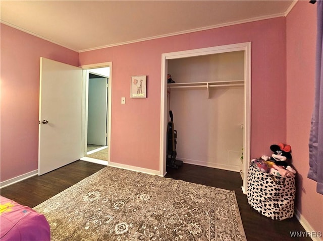 unfurnished bedroom featuring dark wood-style floors, a closet, ornamental molding, and baseboards