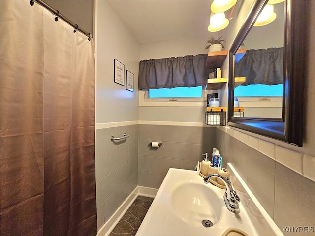 bathroom with a wainscoted wall, a sink, tile walls, and a shower with curtain