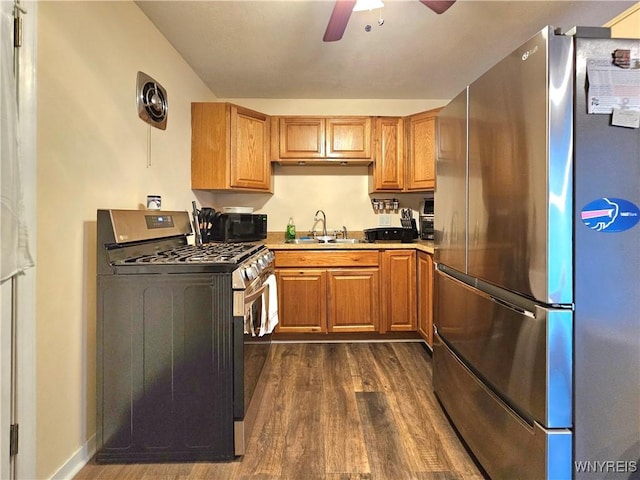 kitchen with ceiling fan, dark wood-style flooring, a sink, appliances with stainless steel finishes, and brown cabinets