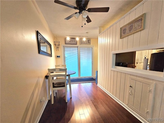 hall with wood walls, baseboards, and wood finished floors