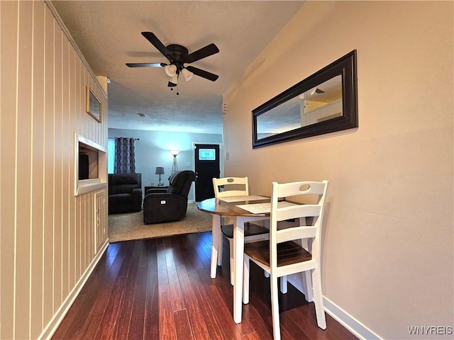 dining space with dark wood-style flooring, ceiling fan, and baseboards