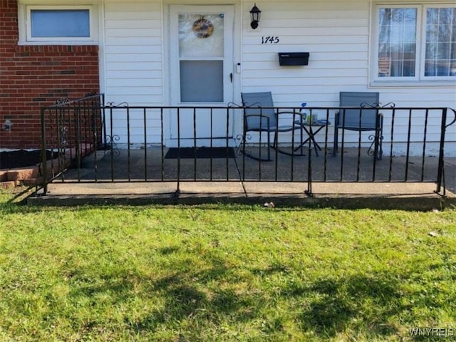 doorway to property featuring fence and a lawn