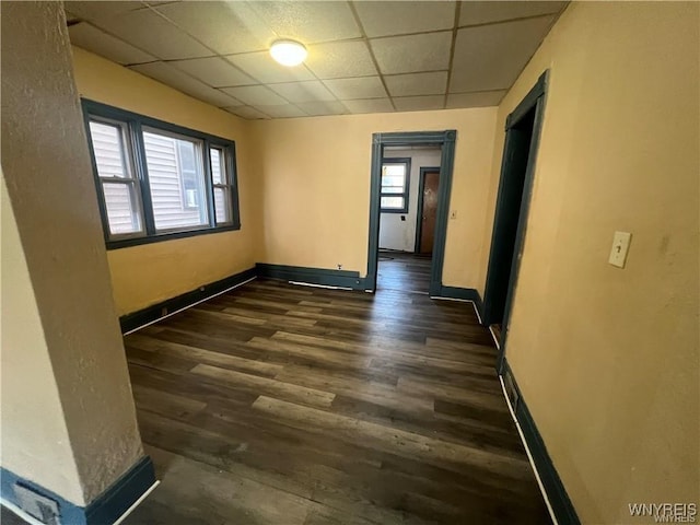 unfurnished room featuring a paneled ceiling, baseboards, and a wealth of natural light