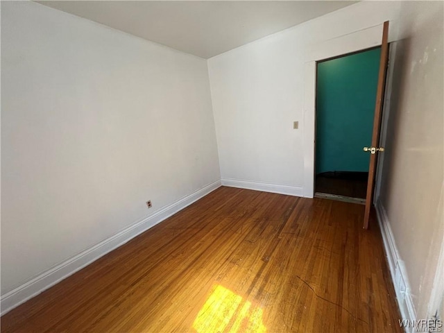 empty room with wood-type flooring and baseboards