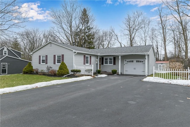 ranch-style house featuring an attached garage, a shingled roof, fence, driveway, and a front yard