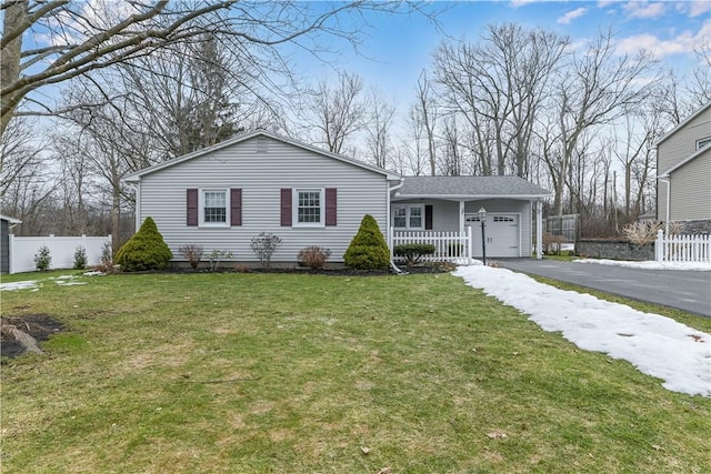 view of front of property featuring a front yard, fence, driveway, and an attached garage