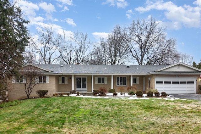 ranch-style home featuring driveway, brick siding, an attached garage, and a front yard