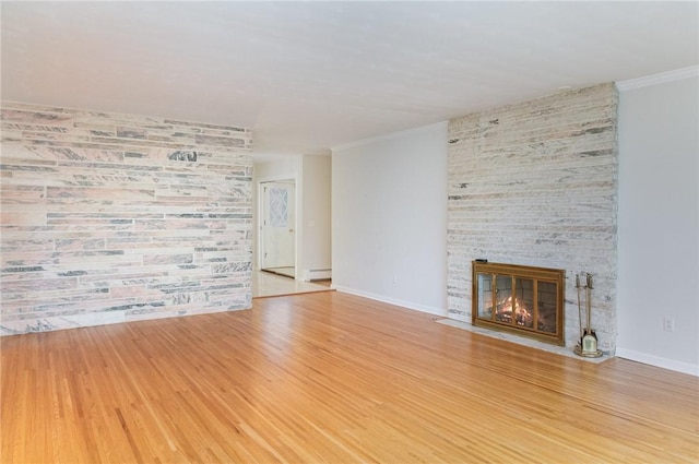 unfurnished living room featuring baseboards, a fireplace, wood finished floors, and crown molding