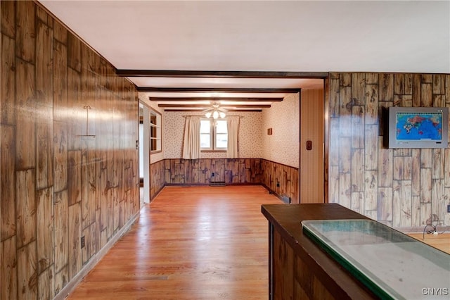 interior space featuring wallpapered walls, a wainscoted wall, light wood-style flooring, beamed ceiling, and wood walls