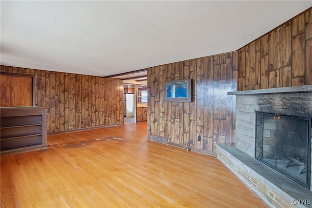 unfurnished living room featuring wood walls, a fireplace, and wood finished floors