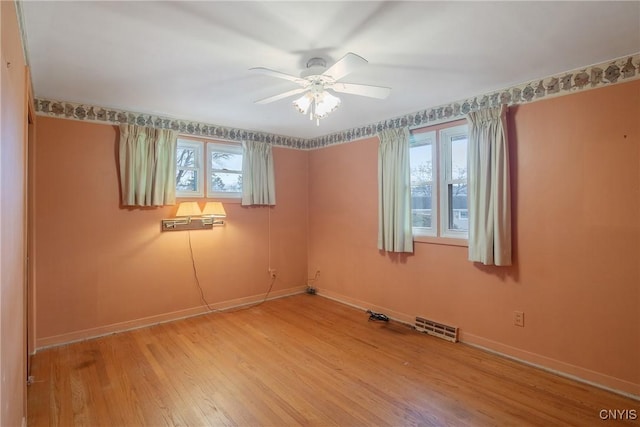 spare room with a wealth of natural light, visible vents, baseboards, and wood finished floors