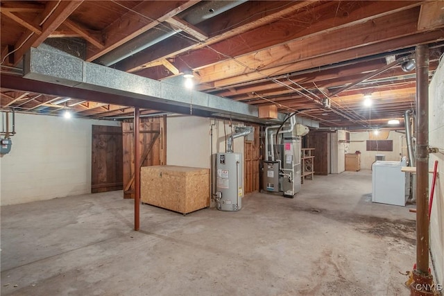 unfinished below grade area featuring heating unit, water heater, and washer / clothes dryer