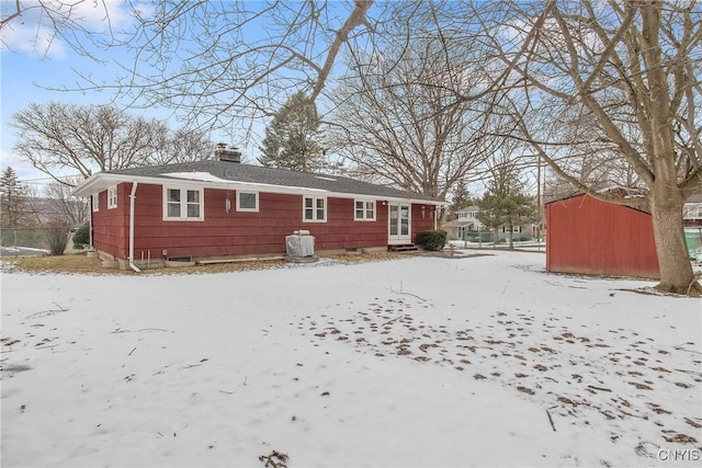 snow covered back of property featuring an outbuilding and a chimney