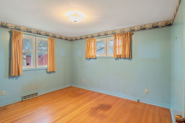 spare room featuring light wood finished floors, baseboards, and visible vents