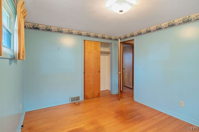 empty room with light wood finished floors, baseboards, and visible vents