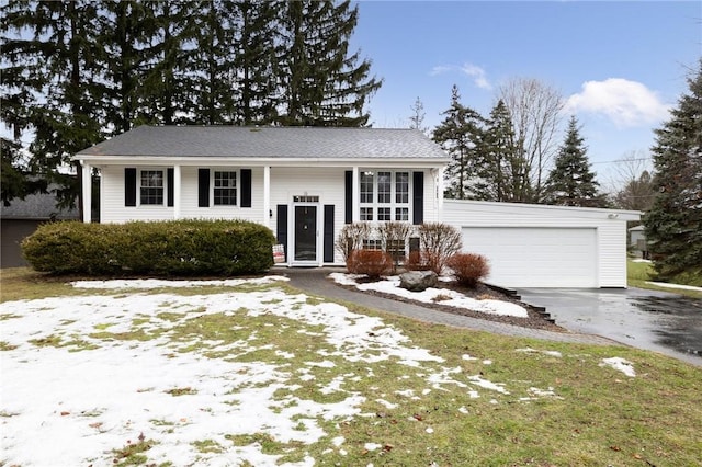 split foyer home featuring covered porch, driveway, and an attached garage