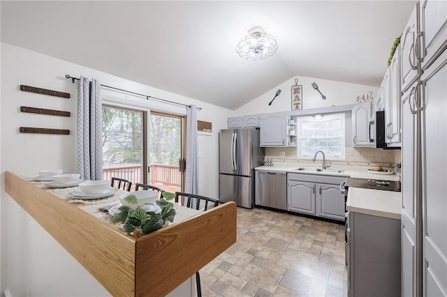 kitchen with stone finish floor, appliances with stainless steel finishes, light countertops, gray cabinetry, and a sink