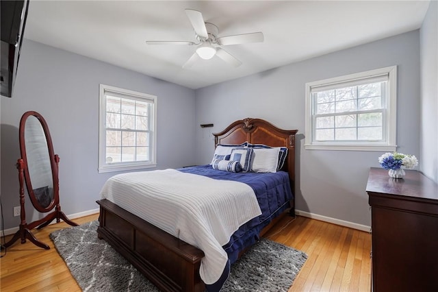 bedroom featuring light wood finished floors, multiple windows, and baseboards