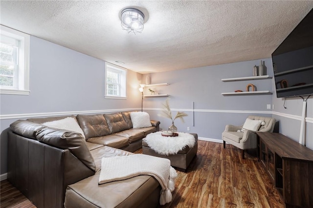 living room featuring visible vents, a textured ceiling, baseboards, and wood finished floors