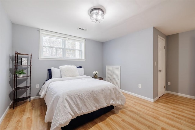 bedroom featuring light wood-style floors, visible vents, and baseboards