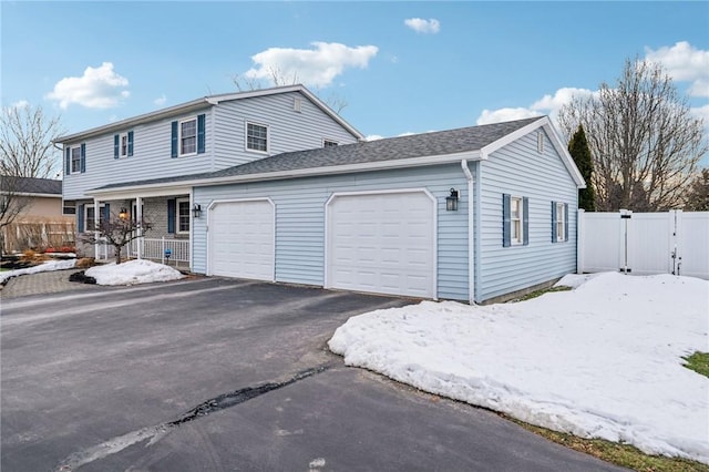 view of front of home featuring driveway, an attached garage, fence, and a gate