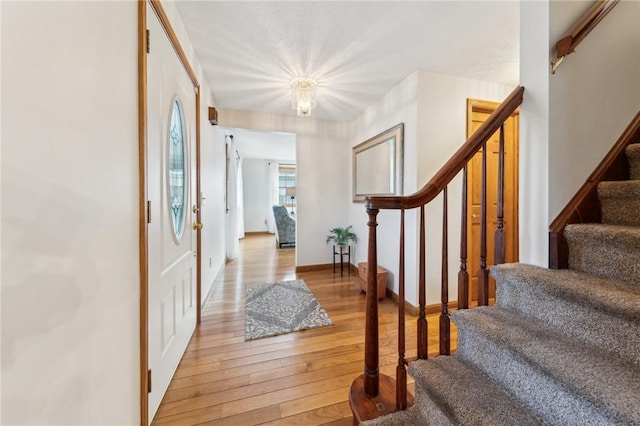 foyer entrance with light wood-style flooring, stairs, and baseboards