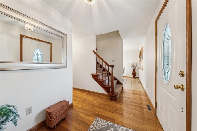 foyer entrance featuring plenty of natural light, hardwood / wood-style flooring, visible vents, and stairway