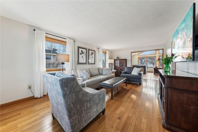 living area with a textured ceiling, light wood finished floors, and baseboards