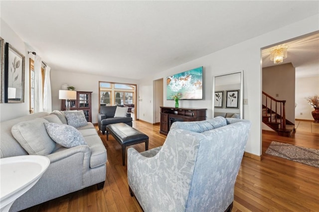 living room featuring wood-type flooring, stairway, and baseboards