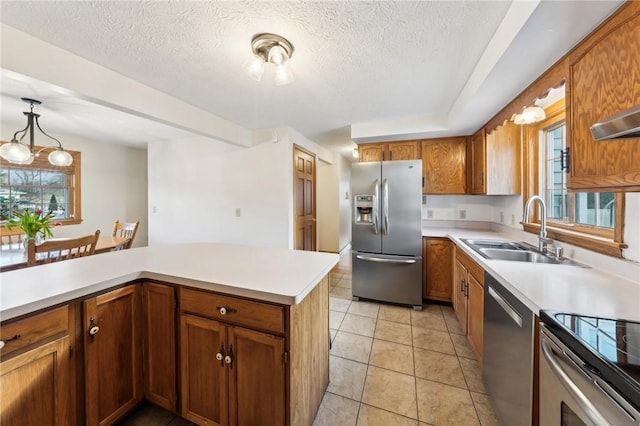 kitchen featuring stainless steel appliances, brown cabinetry, light countertops, and a sink