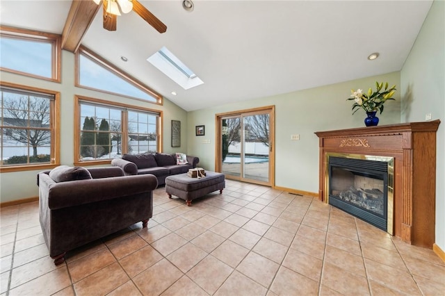 living room featuring light tile patterned floors, beamed ceiling, a glass covered fireplace, and baseboards