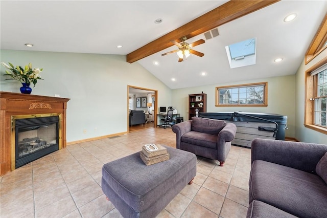 living room featuring vaulted ceiling with skylight, baseboards, a glass covered fireplace, light tile patterned flooring, and recessed lighting