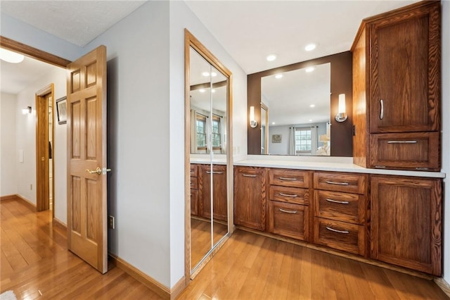 bathroom featuring recessed lighting, wood-type flooring, vanity, and baseboards