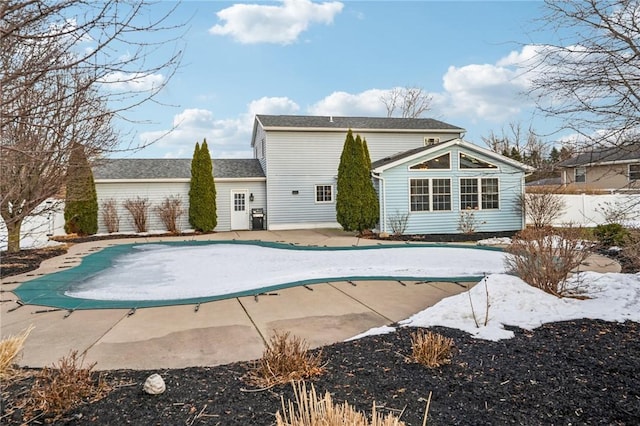 rear view of house with fence, a fenced in pool, and a patio