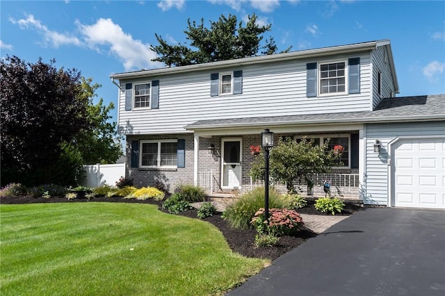 view of front of property featuring an attached garage, driveway, a front lawn, and brick siding