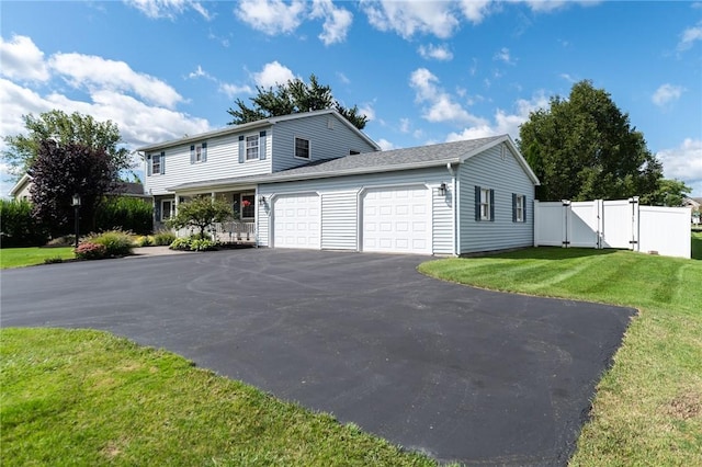 view of front facade featuring a gate, fence, a garage, driveway, and a front lawn