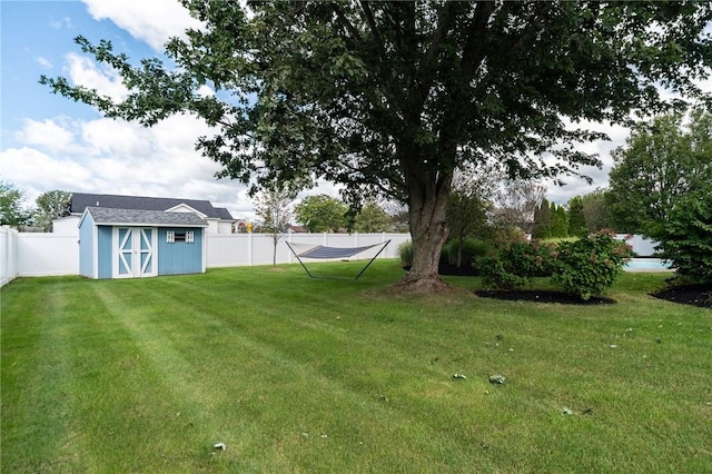 view of yard featuring a storage shed, an outdoor structure, and a fenced backyard