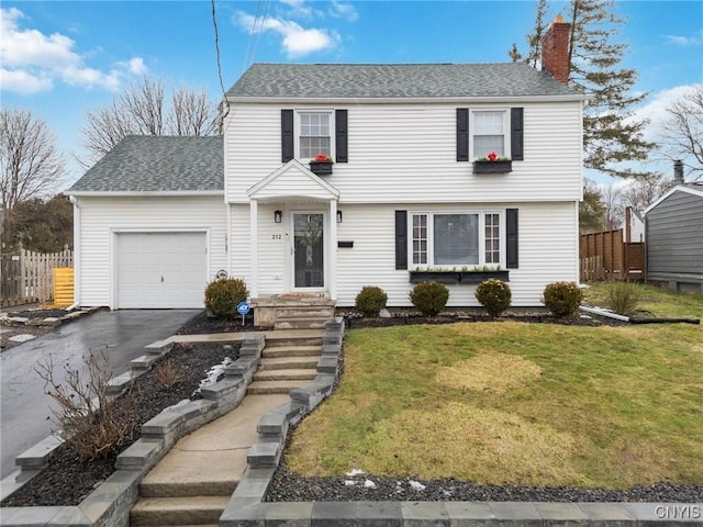 colonial-style house with a garage, fence, driveway, a front lawn, and a chimney