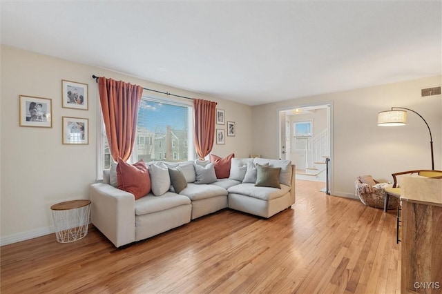 living area featuring light wood-style flooring, visible vents, and baseboards