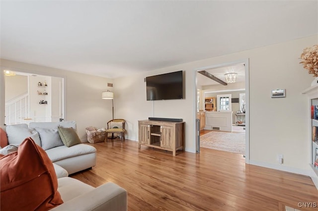 living area with light wood-style floors, stairway, and baseboards