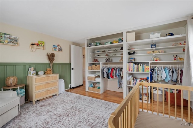 bedroom featuring wainscoting, wood finished floors, and two closets