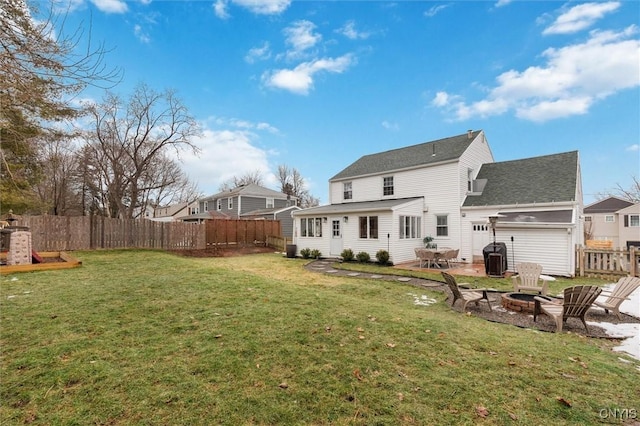 rear view of house featuring a lawn, an attached garage, an outdoor fire pit, a patio area, and fence