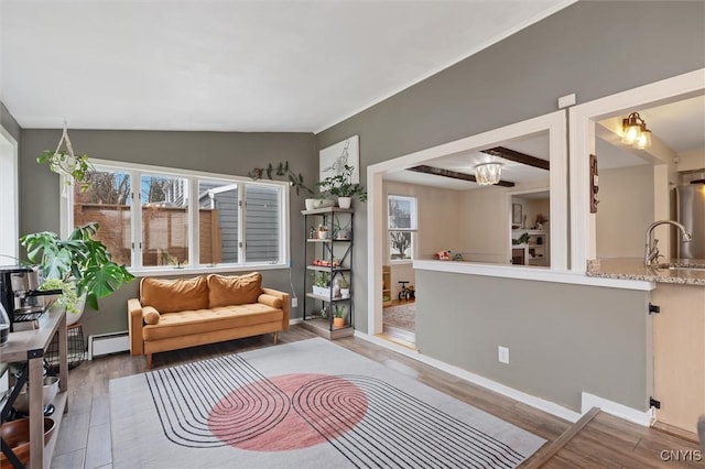 sitting room with lofted ceiling, a baseboard heating unit, and wood finished floors