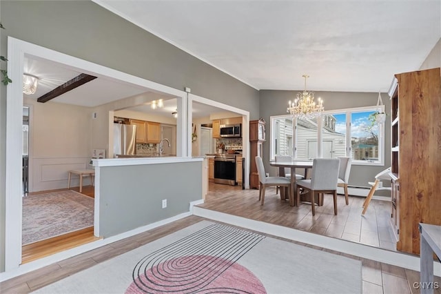 dining space featuring lofted ceiling, wainscoting, light wood-style flooring, and an inviting chandelier