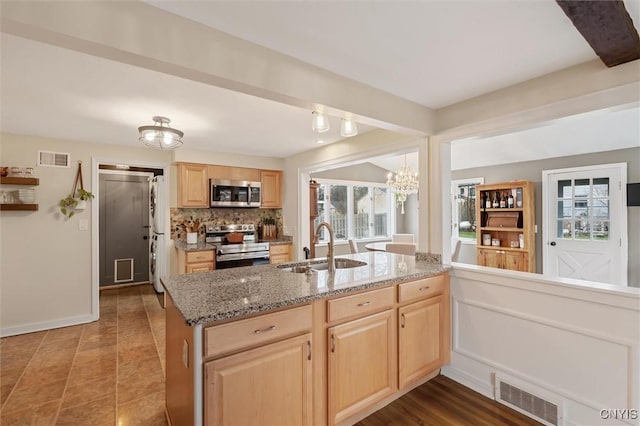 kitchen featuring visible vents, stainless steel appliances, a sink, and light brown cabinetry